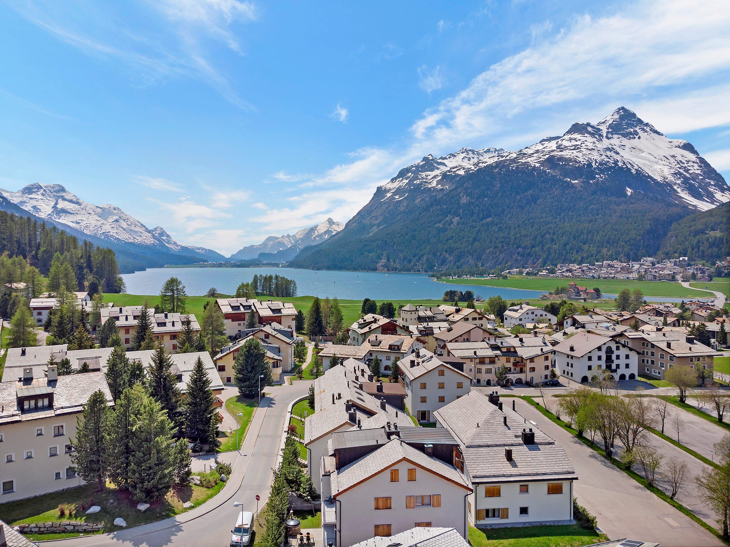 Luftaufnahme eines Bergdorfs mit See und Bergen im Hintergrund