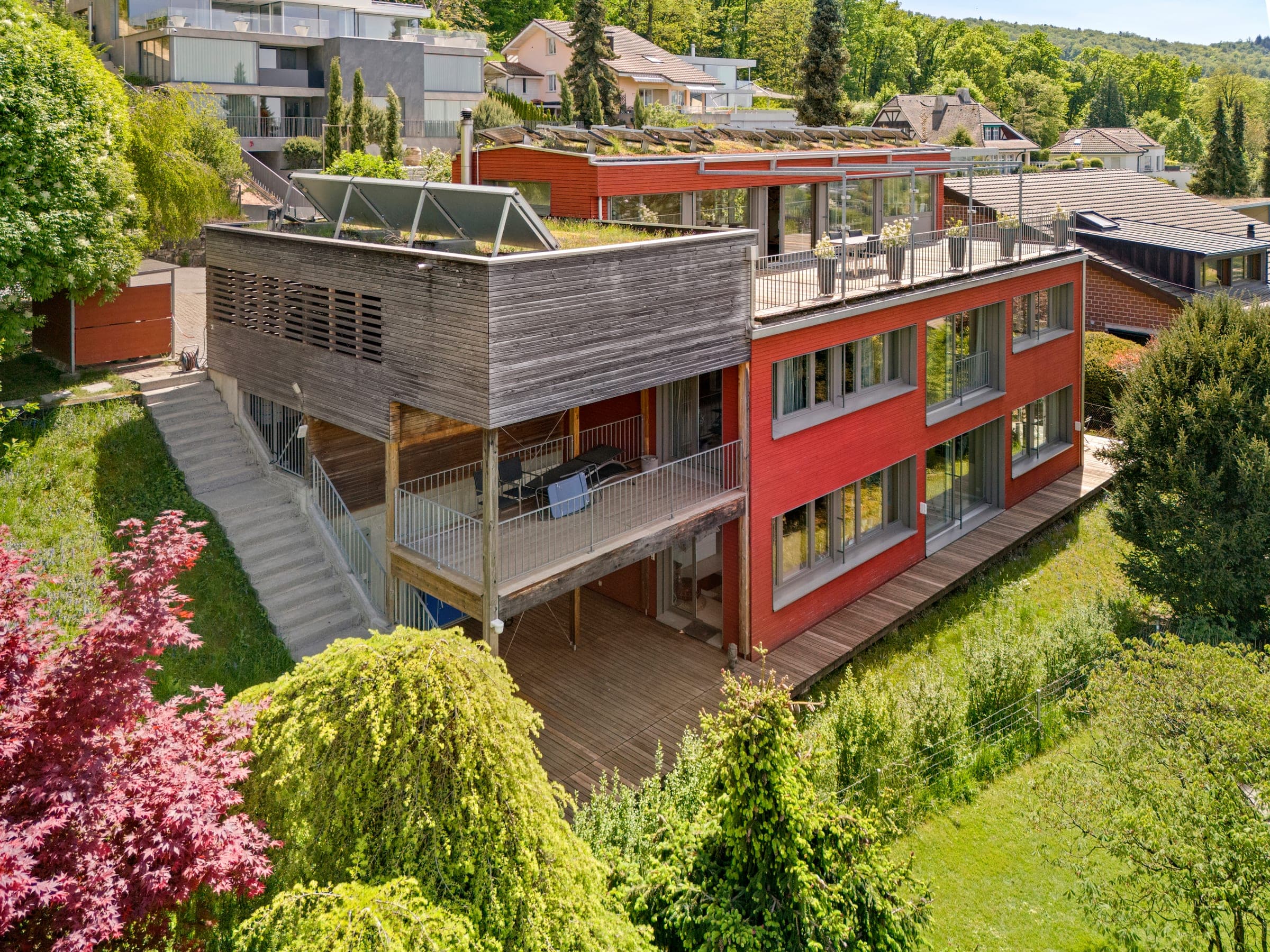 Haus mit roter Fassade und Holzverkleidung am Hang, von oben