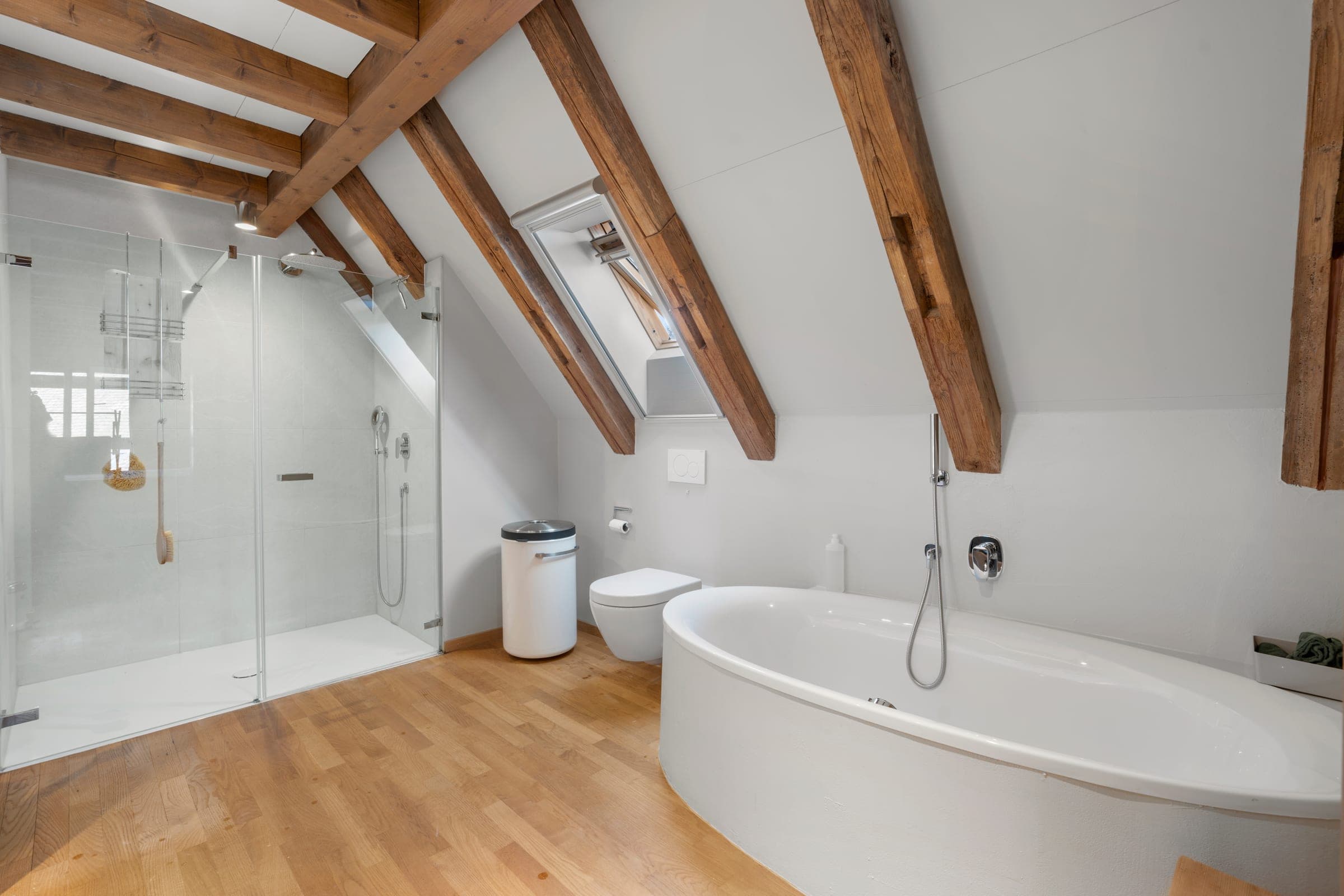 Dachgeschoss-Badezimmer mit Holzbalken und Badewanne