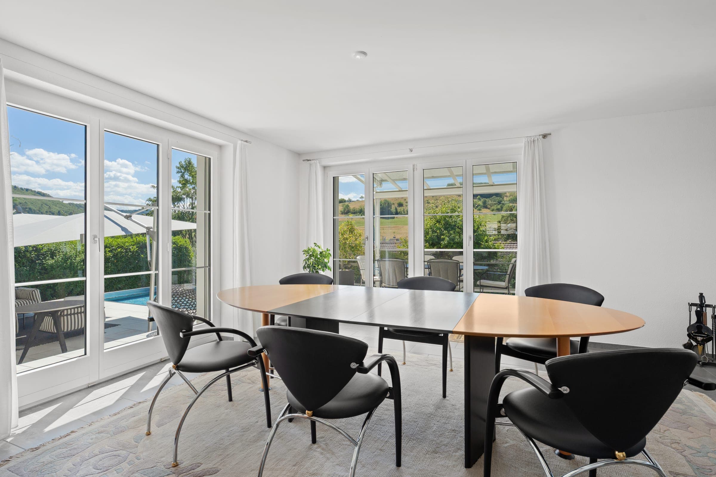 Esszimmer mit Fenstertüren zum Garten und zum Pool